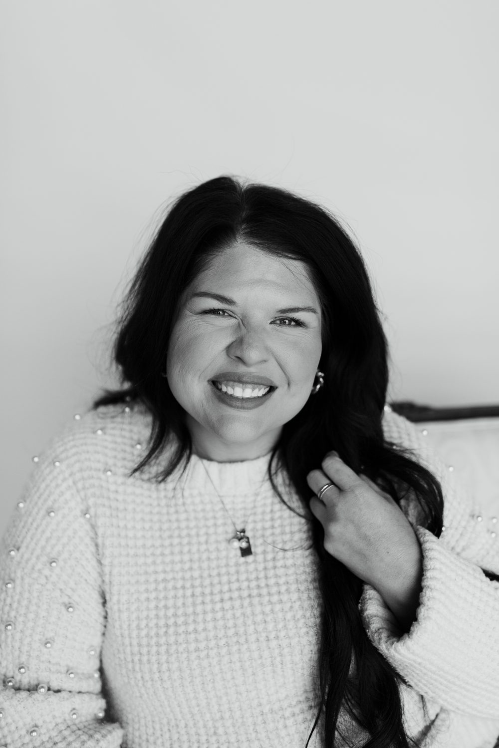 Black and white portrait of Liz Rodriguez smiling, hand in her hair